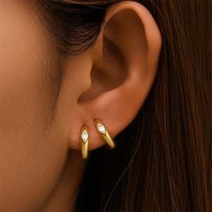Close-up of golden bow-shaped drop earrings with rhombus zircon on female ear