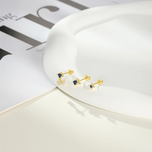 Detail view of gold S925 silver star earrings with blue zircon in a ceramic tray