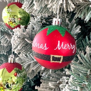 Close-up of red Santa-style Christmas ball with belt detail and Merry Christmas script