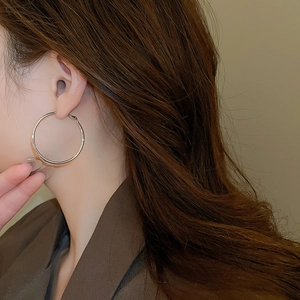 Close-up of a model wearing large silver round hoop earrings for a minimalist look