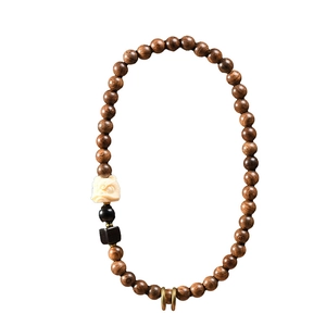 Double-loop sandalwood bracelet with white carved bead and lion accent on white background
