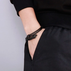 Close-up of black braided steel wire bracelet with detailed wolf head terminals for men