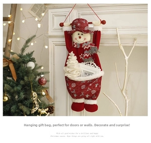 Detail of red Christmas snowman gift bag with striped scarf hanging on white fireplace
