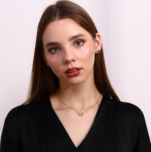 Close-up of golden ribbon bow necklace and stud earrings set on a female model
