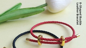 Macro detail of braided leather cord bracelet featuring a gold figure 8 metal clasp