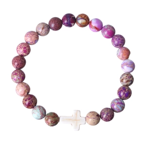 Macro view of purple and colorful stone beads with a white cross pendant on a white background