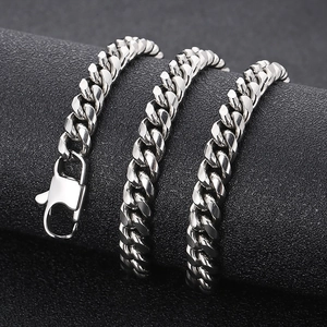 Close-up of a silver stainless steel Cuban link chain with lobster clasp on a dark stand
