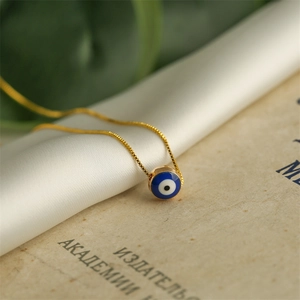 Macro shot of gold Evil Eye necklace on white silk and vintage book background