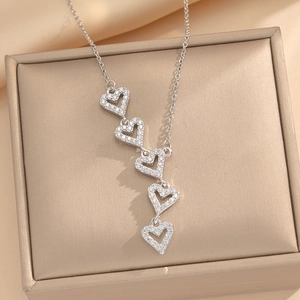 Silver titanium steel heart necklace with five crystal-set pendants on jewelry box