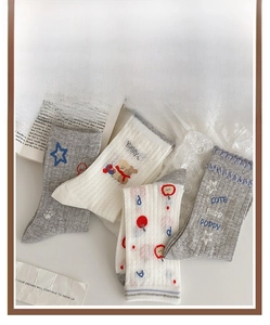 Detail of gray and white knit socks with star and bear embroidery on textured fabric