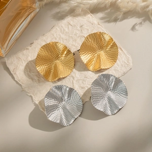Macro shot of gold and silver pleated stainless steel earrings with wavy hammered texture