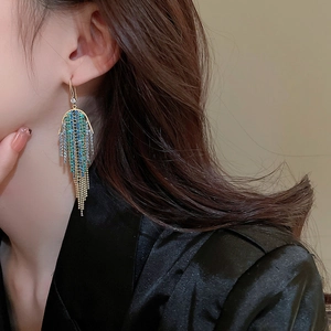 Macro view of long gold tassel earrings with colorful gradient rhinestones on model