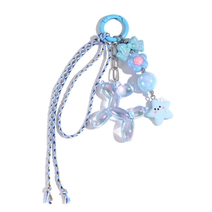 Détail macro du porte-clés chien ballon bleu avec fleurs, étoile et lanière tressée