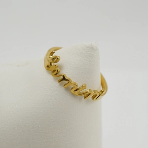 Detailed view of an 18K gold-plated stainless steel zodiac ring with cursive lettering