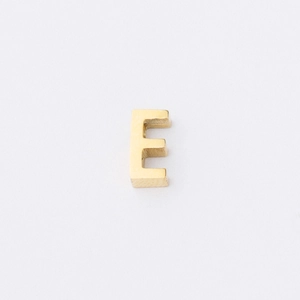 Macro shot of 3D polished golden stainless steel letter E bead for jewelry making