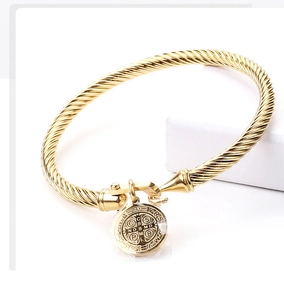 Macro shot of gold twisted cable bracelet with a Saint Benedict medal and U-hook clasp