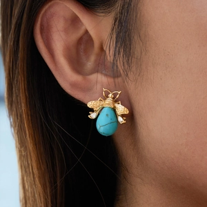 Golden bee earring with turquoise stone and hollow wings worn by a female model