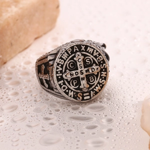 Macro shot of vintage Saint Benedict medal ring on textured background with water drops