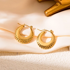 Detailed macro view of gold boat hoop earrings with radiant texture on stone surface