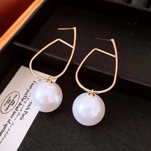 Minimalist gold geometric pearl earrings displayed on black velvet jewelry box