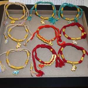 Detail of woven red and cyan cords with golden animal charms on jewelry tray