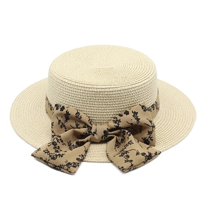 Elegant cream boater straw hat with a brown floral bow ribbon and wide flat brim