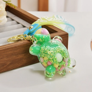 Detail of green turtle keychain with liquid sand, colorful beads and gradient strap
