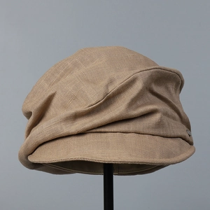 Detailed macro view of tan cotton linen newsboy cap fabric texture and metal logo