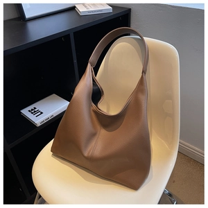 Detail view of camel leather tote bag resting on a chair showing its soft texture and large size