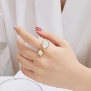 Detailed shot of golden open ring with oval white shell inserts on a person's finger