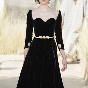 Detail of a golden leaf-shaped metal elastic belt on a black velvet dress