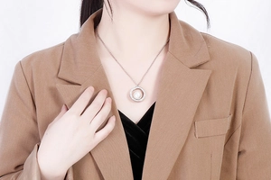 Elegant getragene Edelstahlkette mit rundem Perlenanhänger und einem Kranz aus Kristallen