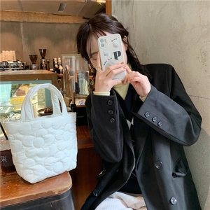 Quilted floral tote bag in white fabric shown in a cafe setting with handheld style