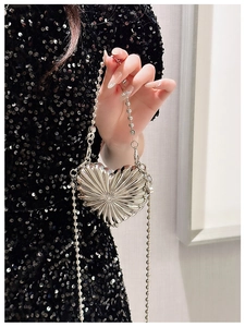 Close-up of heart-shaped silver metallic mini bag with radiant texture and bead chain