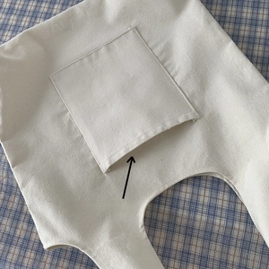 Macro detail of plain canvas tote bag showing the front large pocket design and stitching