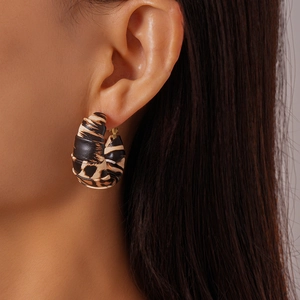 Detailed close-up of C-shaped leopard print earrings with textured leather wrap finish