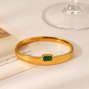 Detail of gold vertical texture bangle with rectangle emerald green gemstone inlay