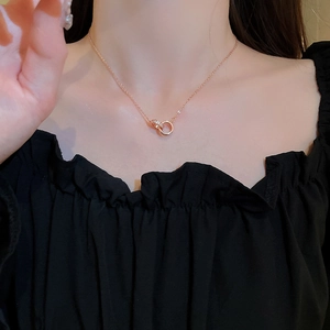 Close-up of interlocking rose gold double hoop necklace with zircon accents on fabric