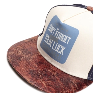 Close-up of hip-hop cap featuring cracked leather brim and embroidered letter patch