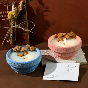 Detail of stone textured candle cups with dried rose buds and warm cozy ambient lighting