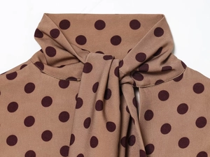 Detailed view of the brown polka dot dress featuring a retro bow tie neck design