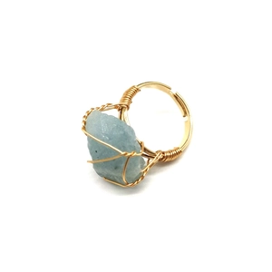 Macro view of adjustable gold wire wrapped ring featuring raw light blue agate stone
