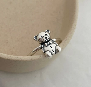 Close-up of 925 sterling silver bear ring with vintage stitch texture on ceramic bowl