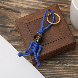 Detail of blue paracord skeleton keychain with brass helmet on a wooden box