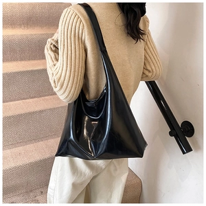 Dettaglio di una borsa tote in ecopelle nera lucida indossata da una modella