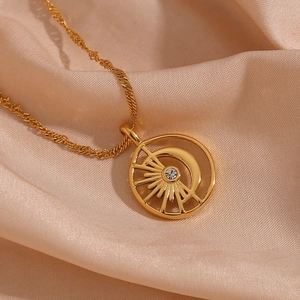 Close-up of 18K gold plated necklace with hollow sun and moon pendant on silk