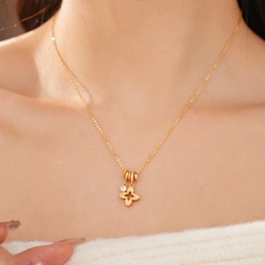 Detailed close-up of a gold hollow four-leaf flower pendant necklace with sparkling zircon