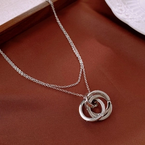 Detailed view of silver interlocking triple ring pendant on a textured fabric background