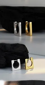Macro detail of polished square S925 silver hoop earrings in gold and silver finish