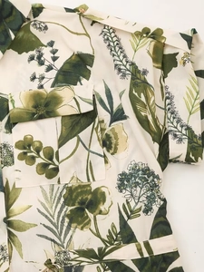 Detail of green leaf print shirt featuring chest pocket and woven fabric texture